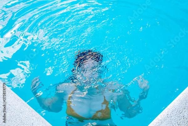 Fototapeta Chica aguantando la respiración dentro del agua en una piscina.