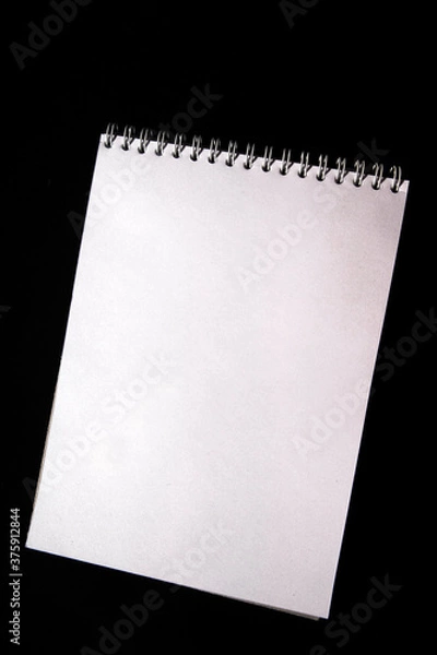 Obraz White notebook paper sheet isolated on black background. Top view