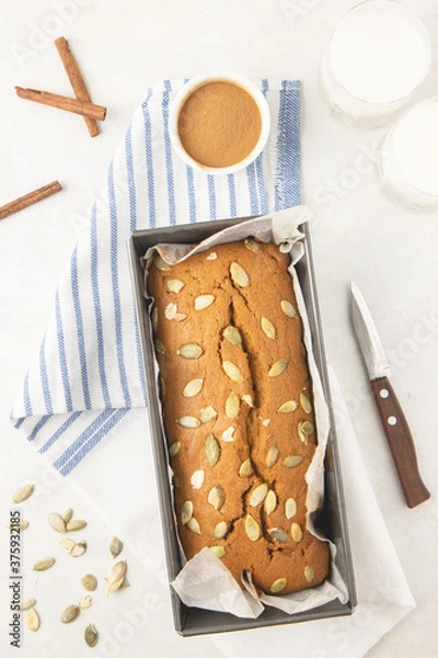 Obraz Fresh homemade pumpkin bread in pan with pumpkin puree, cinnamon, nutmeg and seeds, photographed overhead.