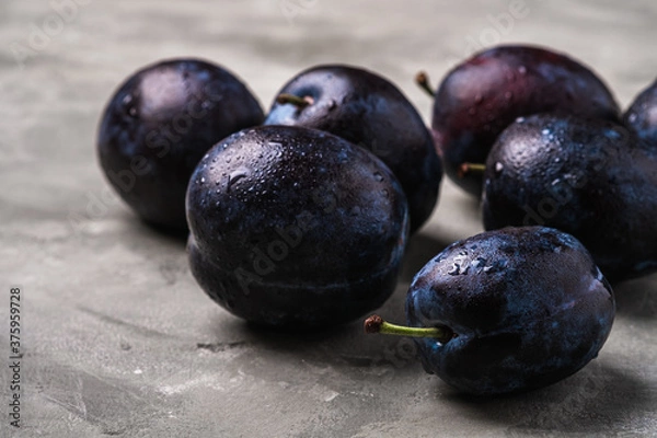 Fototapeta Fresh ripe plum fruits with water drops on stone concrete background, angle view macro