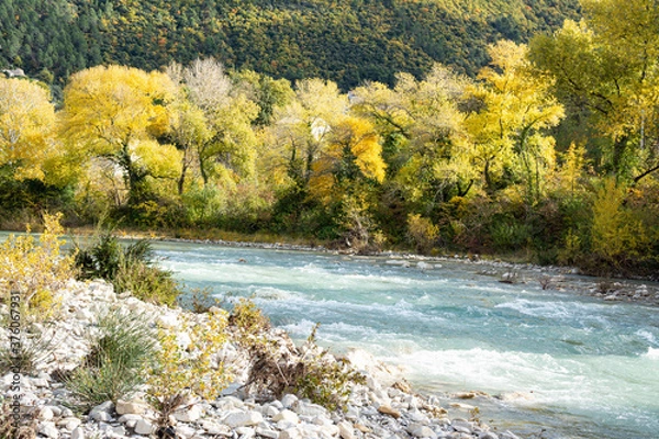 Obraz A river in Provence flows between stones and pebbles. Trees with autumnal colors. Bunches of shrubs grow in the rocky outcrops.