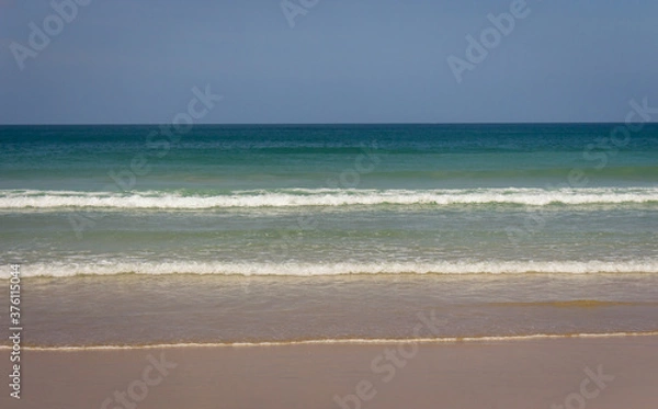 Fototapeta Seascape in Asia. Waves on wide empty beach. Tourist resort. Lagoon landscape. Idyllic vacations concept. Tropical nature. Sea and ocean background. Empty seashore.