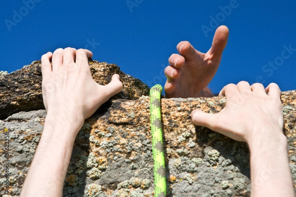 Obraz Rock climber reaching for helping-hand partner.