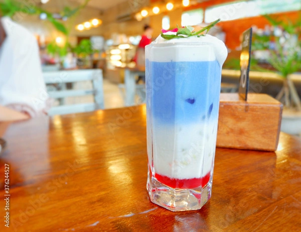 Fototapeta Fresh blue milk juice over coconut milk with ice in glass on wood table. The blue milk is popular menu for order. The taste is delicious. Close up.