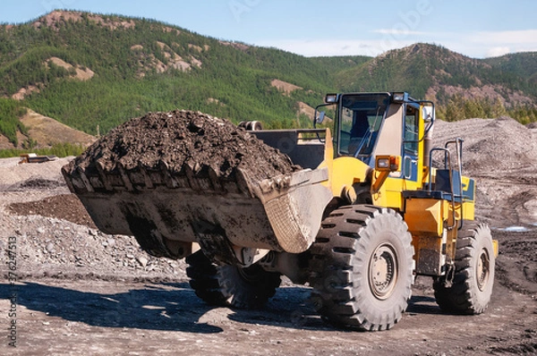 Fototapeta Front-end loader in the mode of transporting mountain soil. Earthworks in mountainous areas.