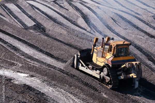 Fototapeta Bulldozers in mountainous wooded areas, layer by layer, remove mountain soil from the surface and shovel it to the side.