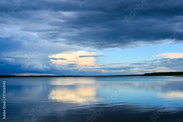 Fototapeta A calm evening sky landscape of pastel colors with a reflection in the smooth waves of a large lake. Natural background