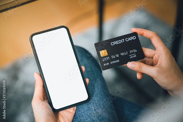 Fototapeta Woman hand using smartphone and holding credit card with payment online on mobile.
