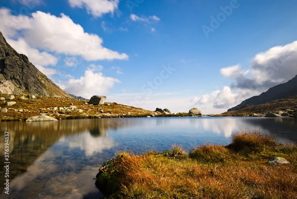 Fototapeta Long exposure closeup of a mountain lake with a reflection on a cloudy autumn day