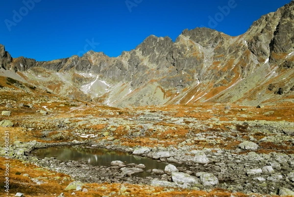 Fototapeta Mountain lake between rocks on a clear autumn day