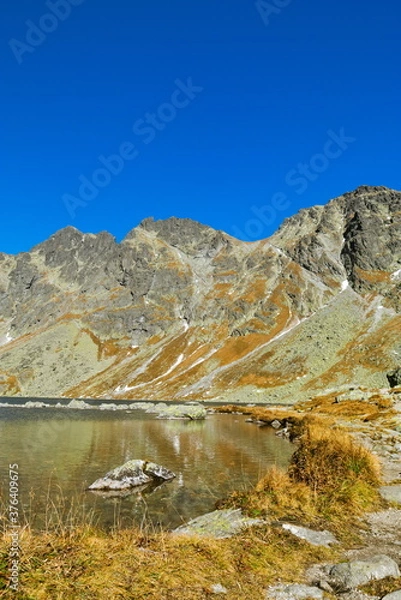 Fototapeta Shore of a mountain lake in autumn under a clear sky