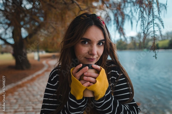 Fototapeta Close up shot of a pretty caucasian woman holding a cup of coffee to go