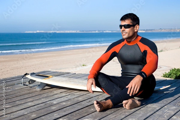 Fototapeta Surfer wearing a wetsuit with surf board.