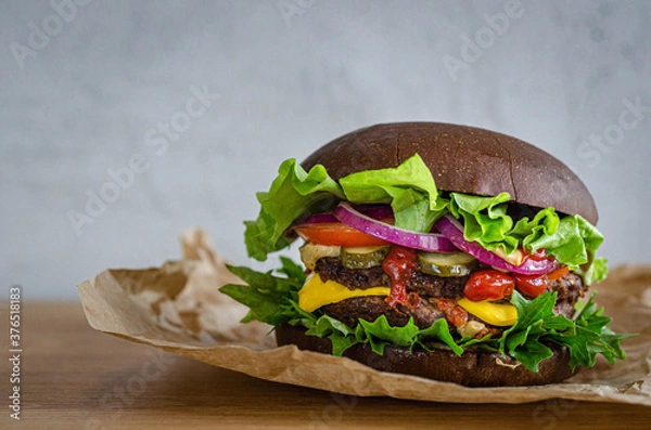 Obraz juicy powerful burger with beef and vegetables on a rye bun.