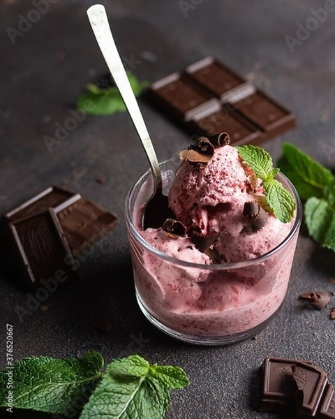 Fototapeta berry ice cream with chocolate in a glass with a spoon on a gray surface, next to mint