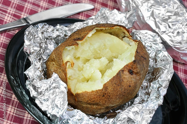 Obraz One open baked potato on aluminum foil, unwrapped.