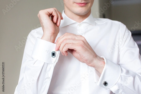 Obraz a man in a white shirt adjusts his bow tie