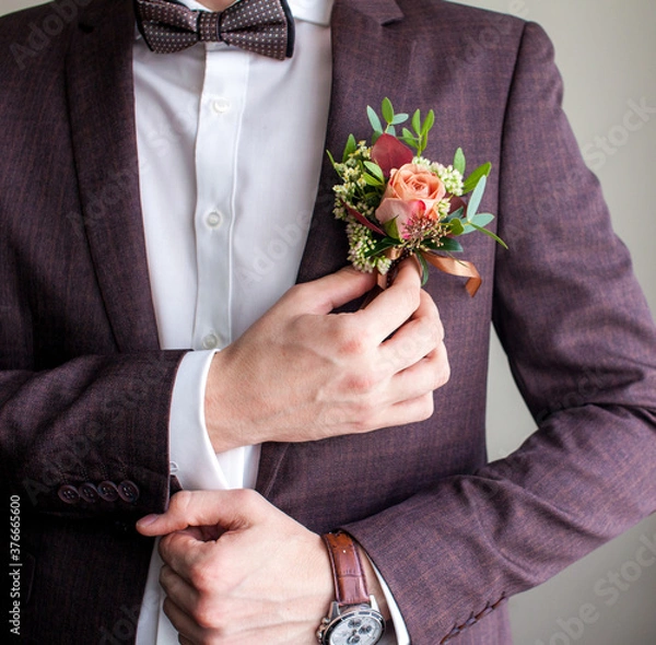 Obraz a man in a wedding suit adjusts a boutonniere