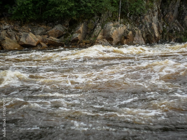 Fototapeta big waves on the rolling threshold of a mountain river against the background of rocks and forests