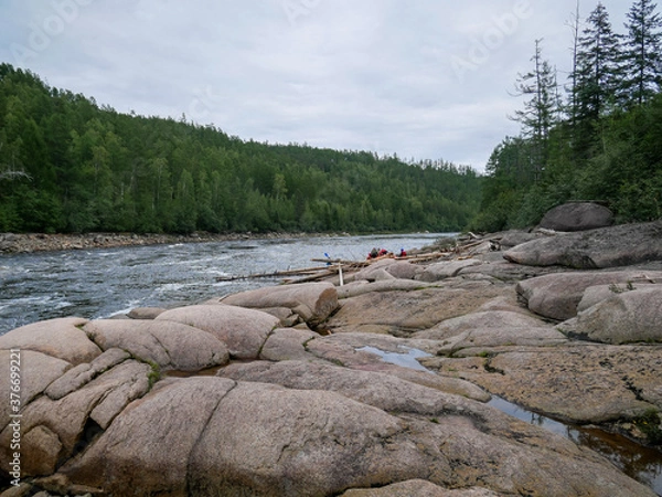 Obraz Rifts and rapids on a mountain river against the background of mountains and forests in summer, large stones and a swimming facility in the distance