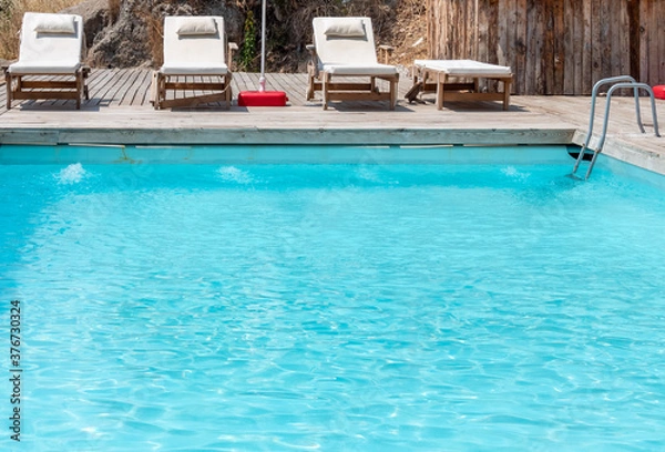 Fototapeta Swimming pool with empty sunbeds.