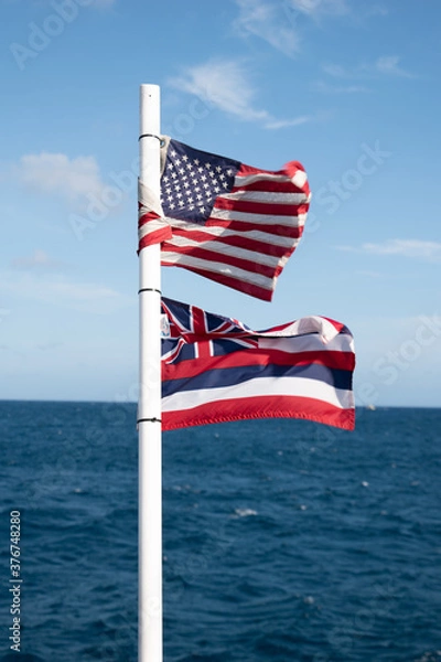 Obraz American flag and Hawaiian flag waving on the back on a boat at a tropical beach in Hawaii Waikiki with deep blue ocean 