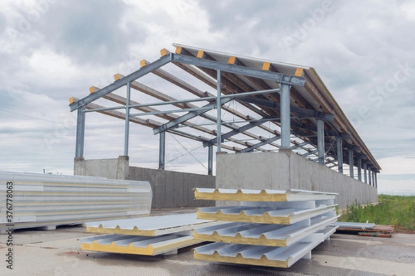 Fototapeta Metal frame of the building with a sandwich panel of insulation on the wall. Construction of a new industrial building. Modern Insulation of the walls of the building panels of insulation.