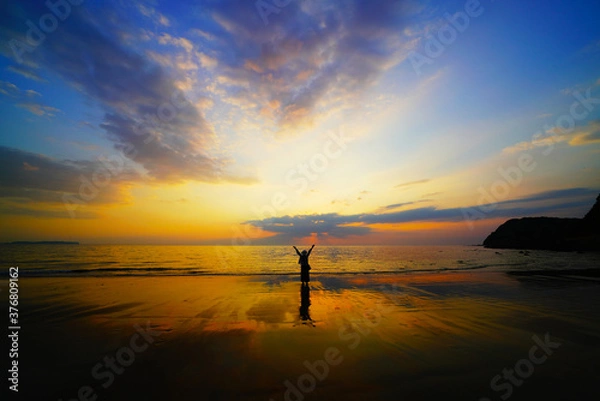 Fototapeta 夕焼けと両手を広げる女性