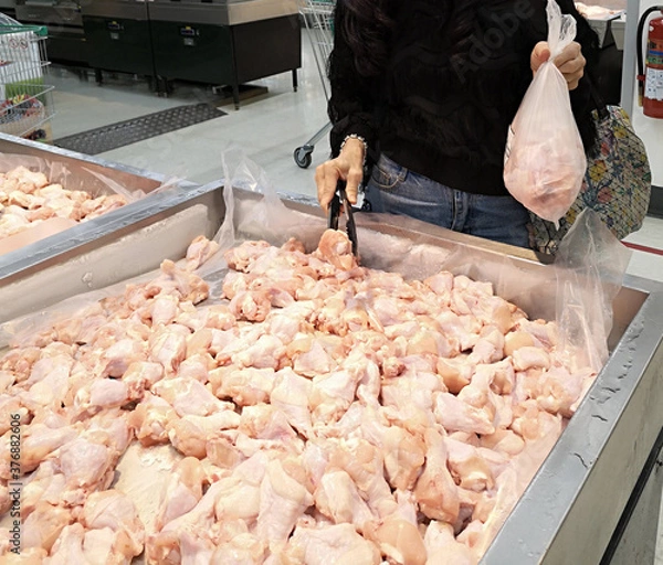 Fototapeta Buying fresh chicken wings arranged on a tray.