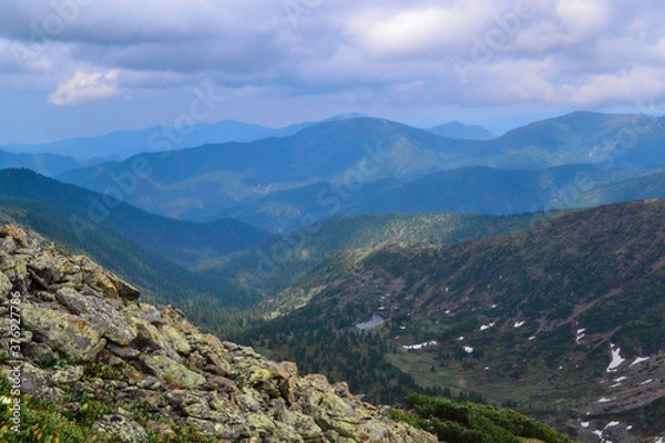 Fototapeta mountain stone slope overgrown with moss grass, bushes and trees in the Baikal green blue mountains, Siberia