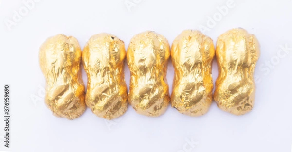 Fototapeta .Chocolate wrapped in gold paper, close-up of a few ounces of chocolate. On a white background