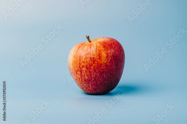 Fototapeta A red apple on a blue studio background