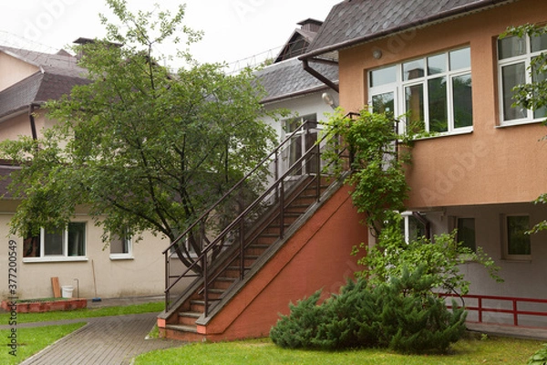 Fototapeta A staircase to the second floor of a two-story house, a sanatorium, a drug treatment clinic, a government institution, a hospital, a rehabilitation center in a forest or park in summer.