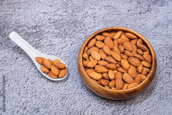 Fototapeta Almonds seed in a wooden bowl on dark background. Healthy food for peple who want to lose weight.