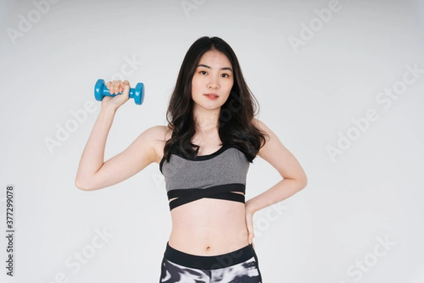 Fototapeta Beautiful slim asian woman work out with dumbbell over white background.