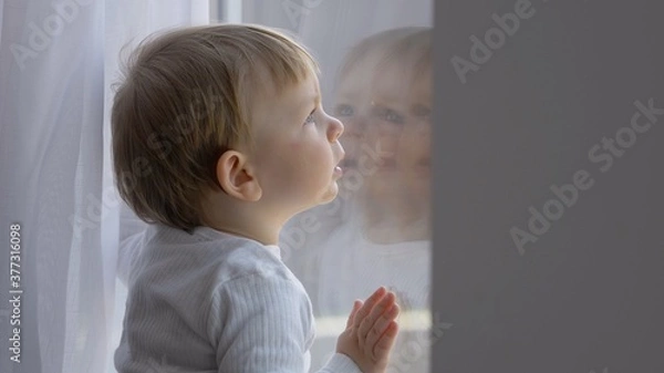 Fototapeta Cute toddler face reflected in window, child looking outside through window during home isolation