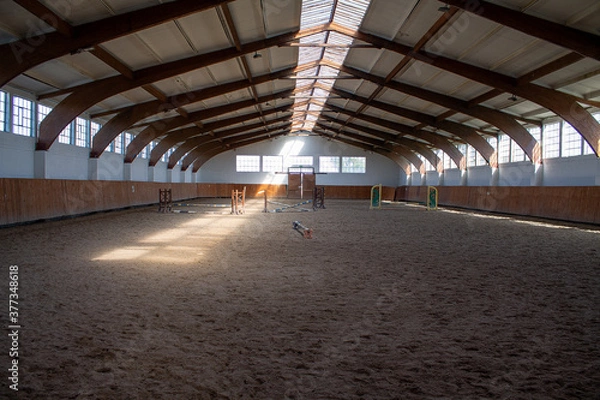 Obraz A light-flooded riding arena with some jumping obstacles.