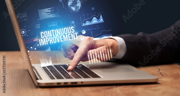 Fototapeta Businessman working on laptop with CONTINUOUS IMPROVEMENT inscription, new business concept
