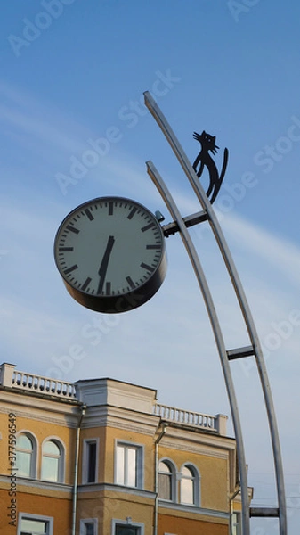 Fototapeta City clock on the street on a sunny day with a silhouette of a cat