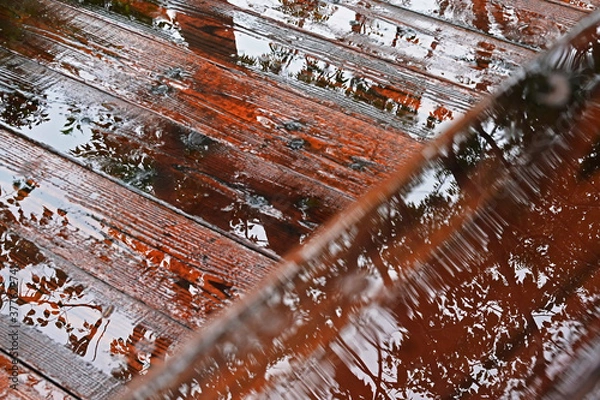 Obraz 雨に濡れた木製の手すりと木の床の水に映る樹木のシルエット