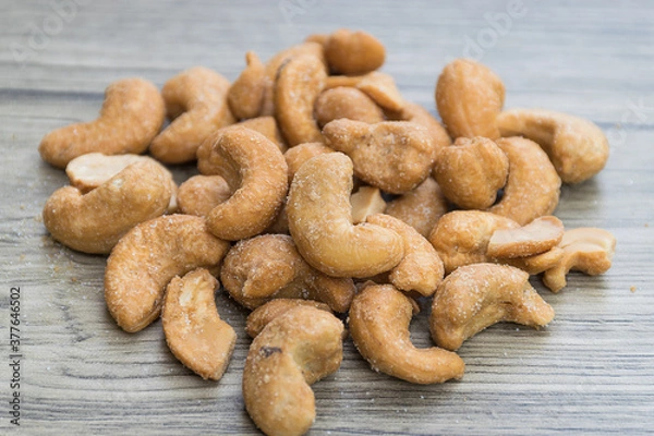 Fototapeta Heap of salted roasted cashew nuts on the wooden table
