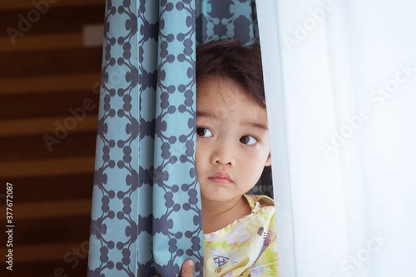 Fototapeta Close up portrait of Asian cute little boy is hiding in the curtain in the patient room in hospital.  Healthcare medical and people concept.