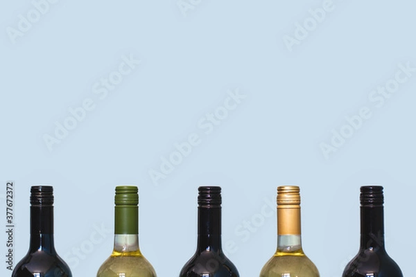 Fototapeta Tops of red and white wine bottles on light background. Space for text