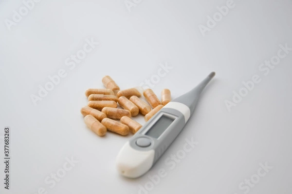 Fototapeta Group of natural pills on a white background with a grey thermometer
