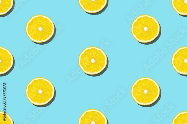 Fototapeta Top view of fresh lemon pattern on blue background. Many sliced yellow lemon texture background. Seamless fruit minimal concept.