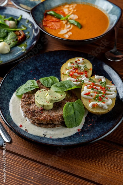 Obraz Grilled pork hamburger with baked rustic potato and rich creamy sauce, close up view, yummy photo