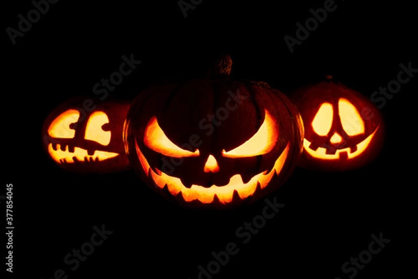 Obraz Three Halloween pumpkins with glowing eyes and mouth on a black background