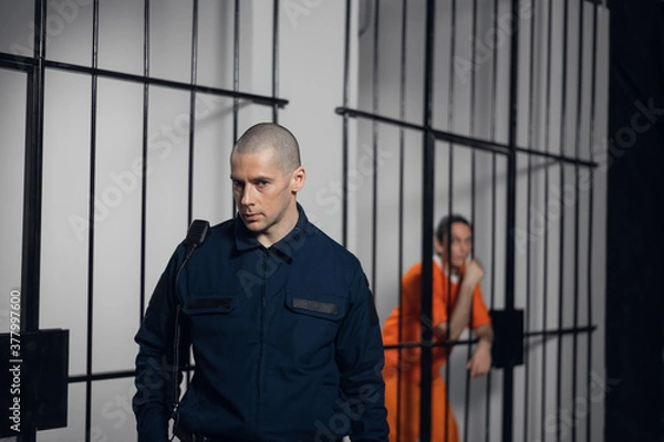 Fototapeta A strict prison guard in uniform guards cells with prisoners in a maximum security prison
