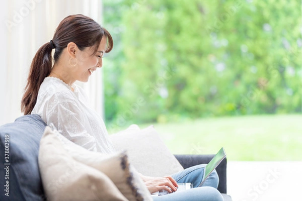 Fototapeta リビングでノートパソコンを使う女性