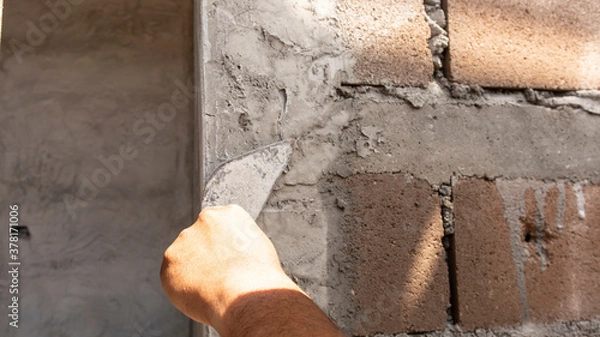 Fototapeta Tiler's hand.bricklayer plaster a wall inside a building